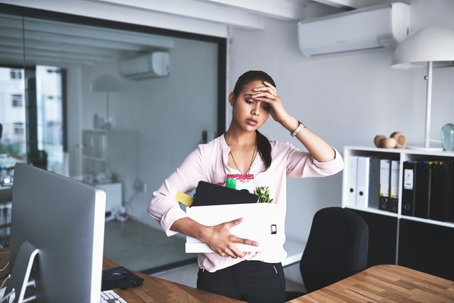 an unhappy businesswoman holding her box of belongings after getting fired from her job